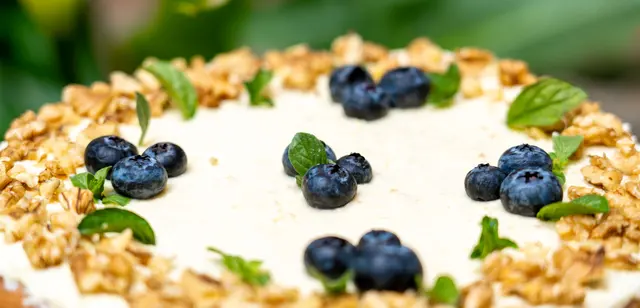 Torta de queso decorada con arándanos, nueces y hojas de menta